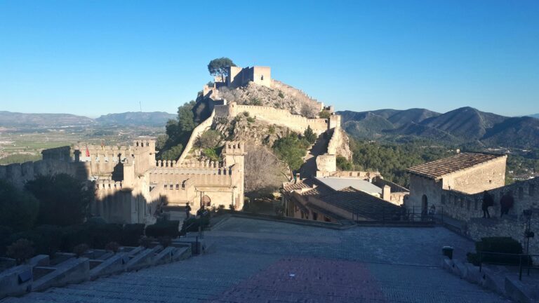 Fotografía real del Castell de Xàtiva con murallas y paisaje de montaña
