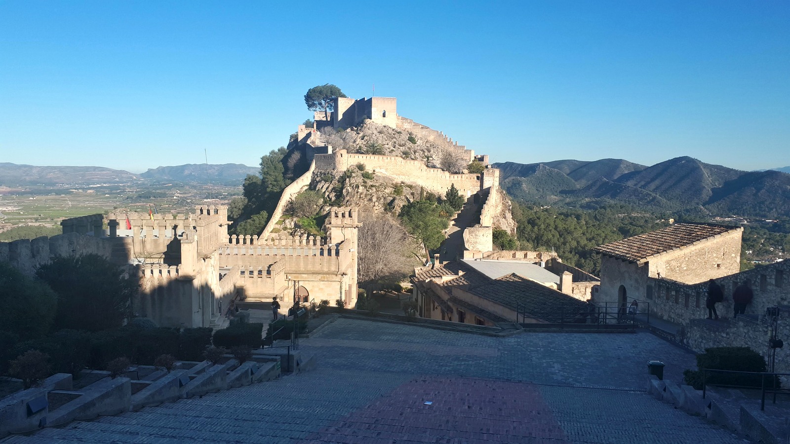 Fotografía real del Castell de Xàtiva con murallas y paisaje de montaña